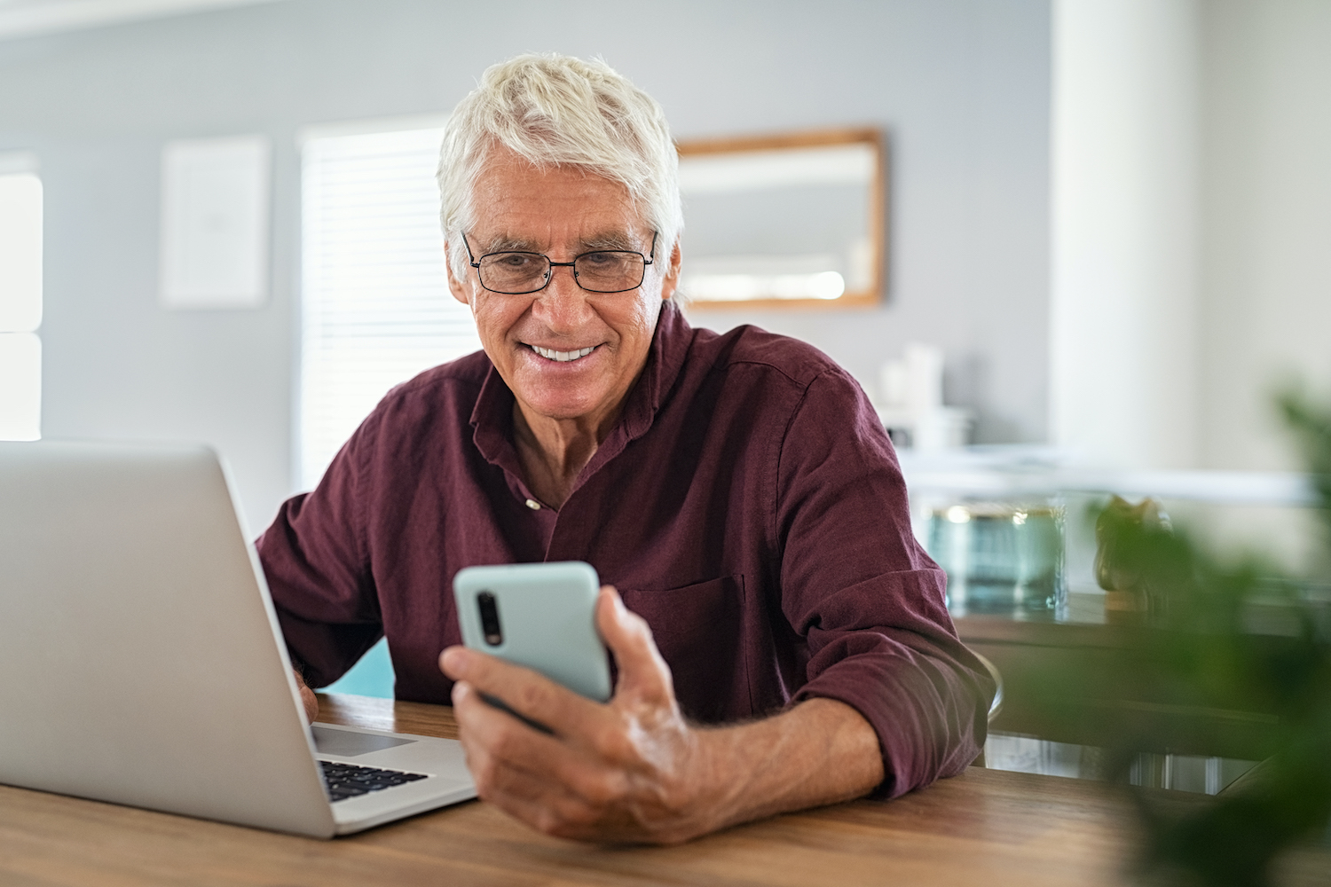 Senior man working on laptop and using smartphone