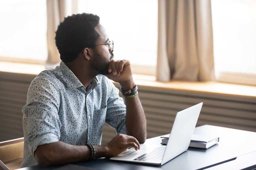 Man looking in the distance while sitting at laptop