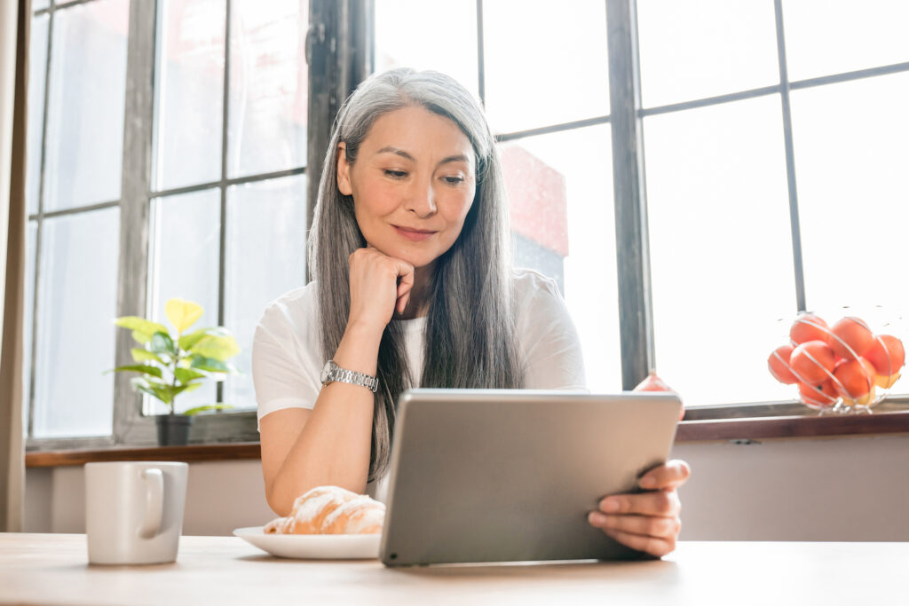 Middle-aged beautiful woman using tablet in the kitchen