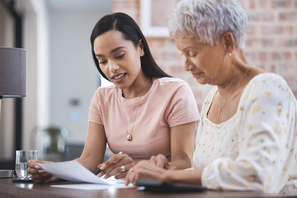 A young woman explaining documentation on a paper to an older woman.
