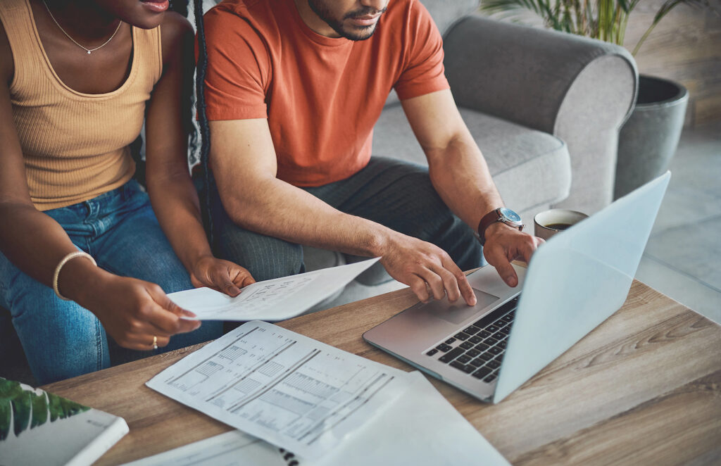 A man and woman analyzing financial papers and reviewing a laptop