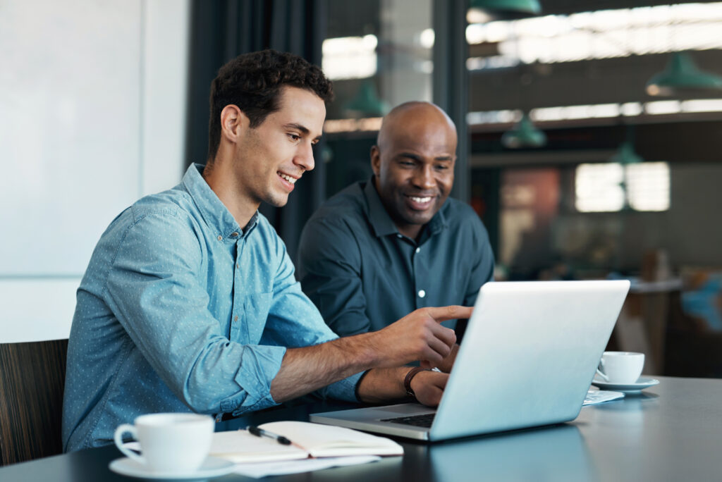 Sales manager planning branding ideas with a creative designer on a laptop in an office.